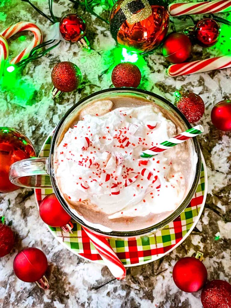 Top view of Holly Jolly Christmas Cocktail topped with whipped cream and surrounded by red ornaments