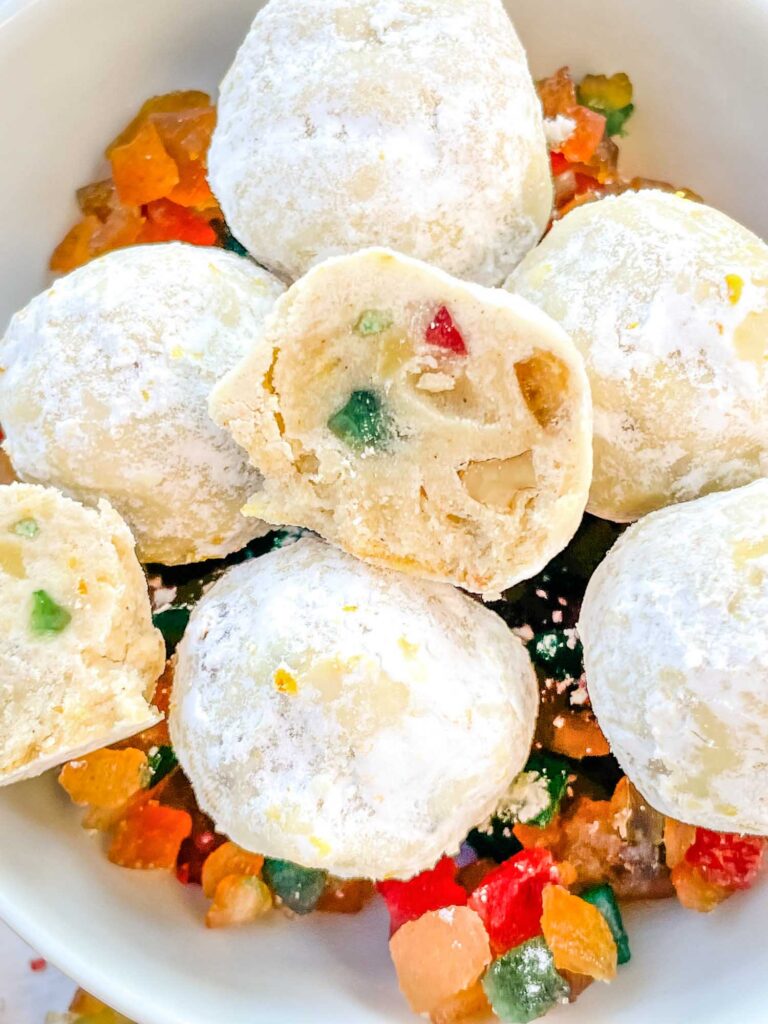 A pile of the Snowball Fruitcake Cookies with one cut open on top