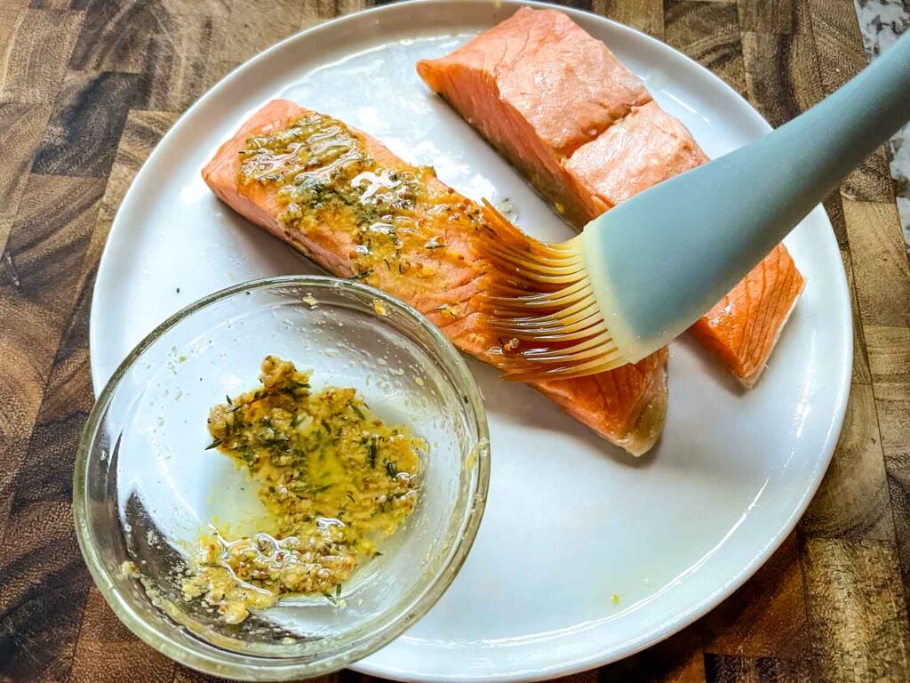 A basting brush putting the cooking sauce onto the fish