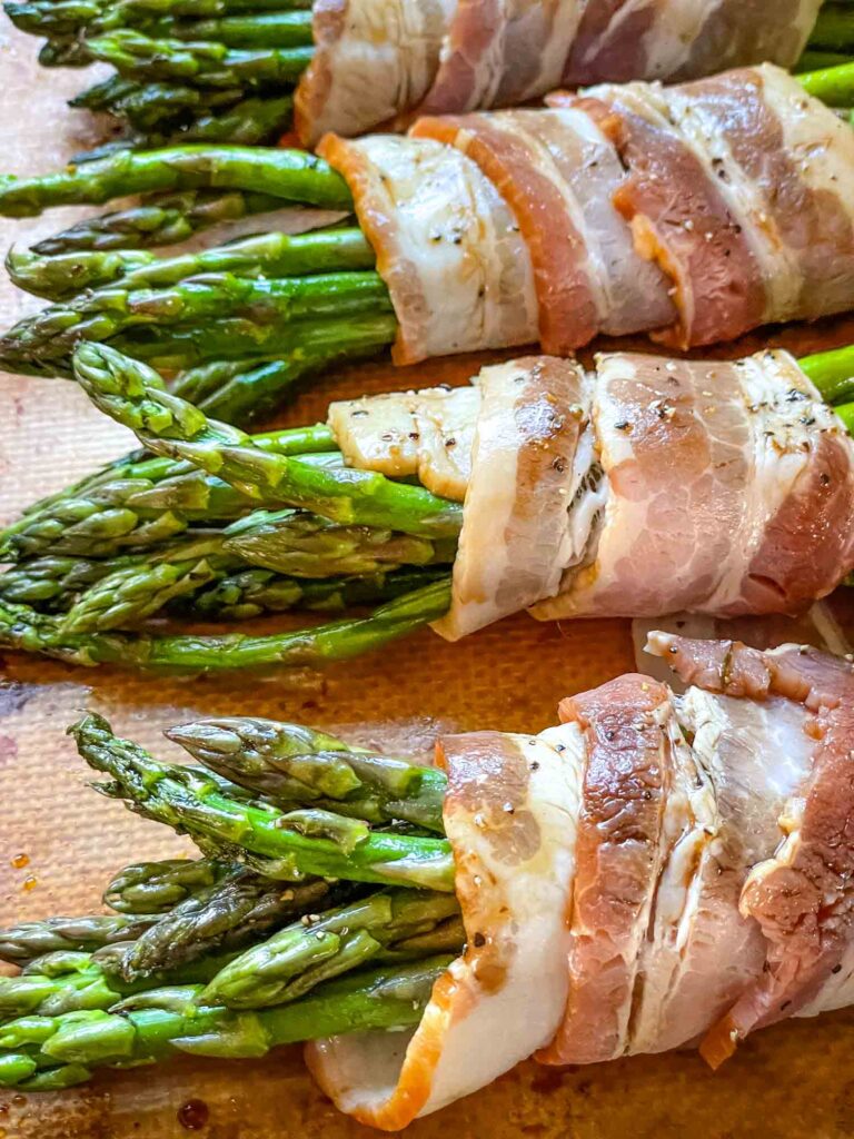 The asparagus bacon bundles lined up on a baking sheet