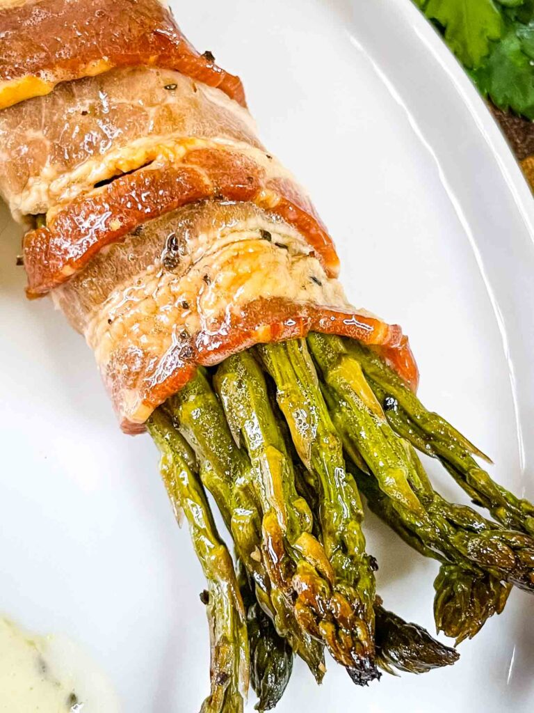 A portion of Asparagus Wrapped in Bacon on a white plate