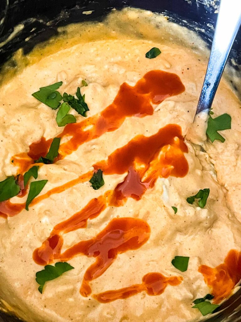 Buffalo Chicken Crockpot Dip with sauce and green onions on top inside the slow cooker