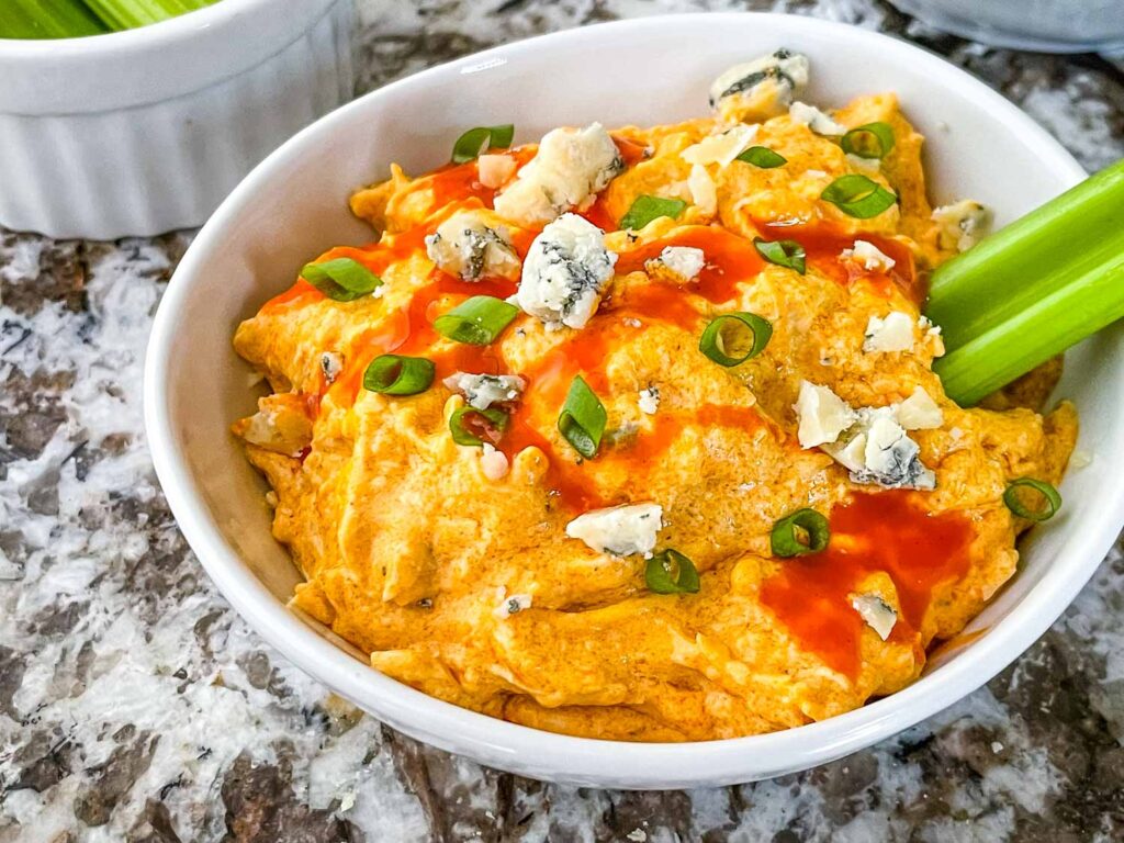 A small bowl full of Buffalo Chicken Crockpot Dip with toppings
