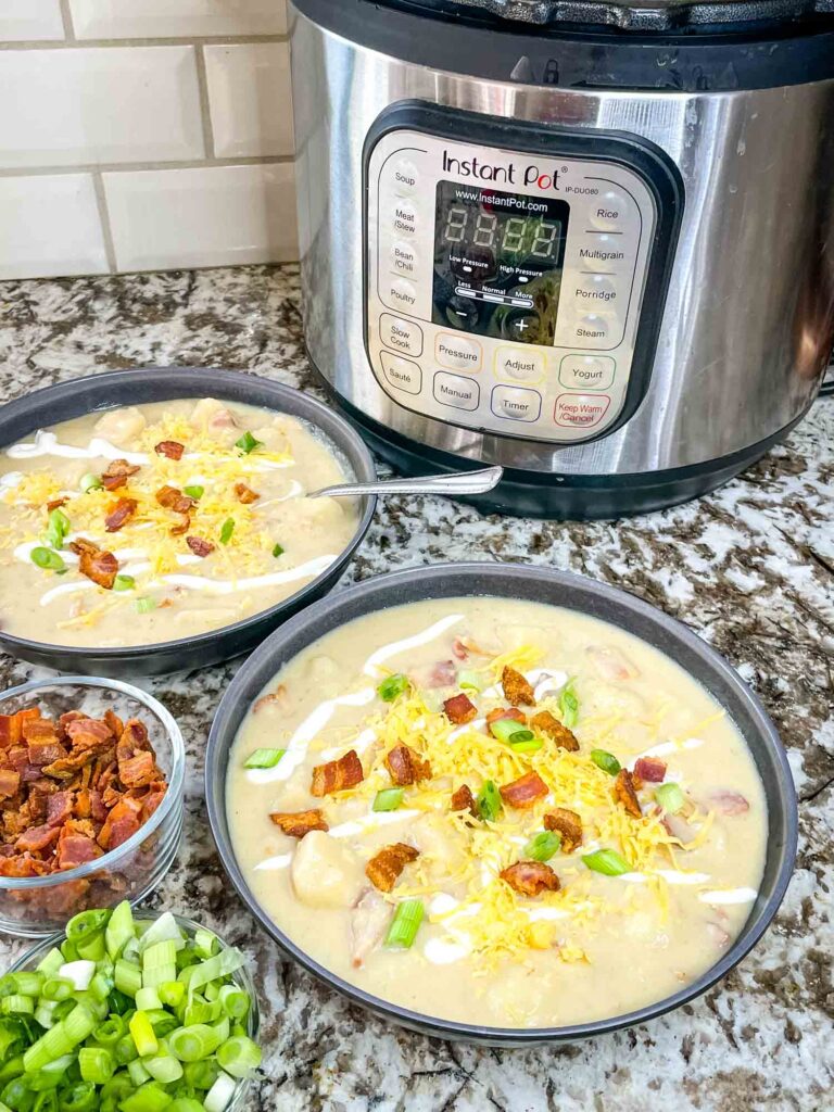 Two bowls of Instant Pot Potato Soup with toppings and an Instant Pot in the background