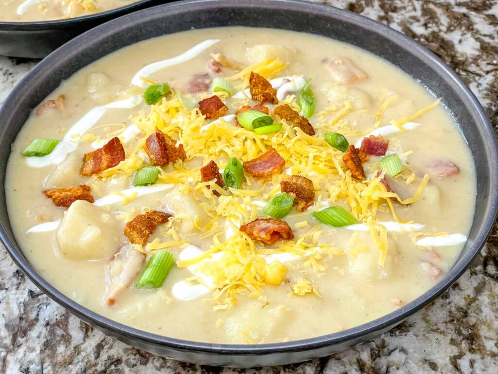 Top view of Instant Pot Potato Soup in a dark gray bowl with bacon and cheese on top