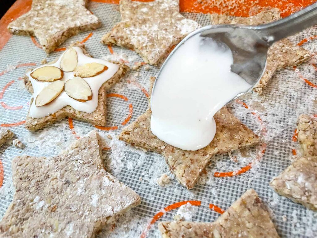A spoon pouring meringue on the almond cookie