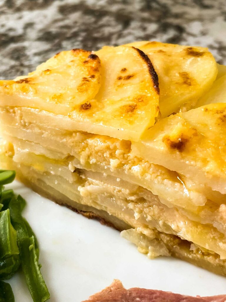 Side view of a portion of Scalloped Cheesy Potatoes on a plate