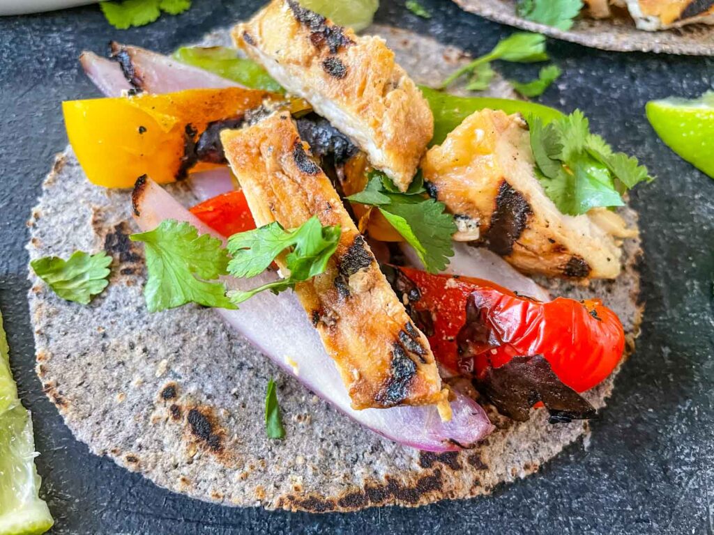 A blue corn tortilla loaded with chicken and peppers