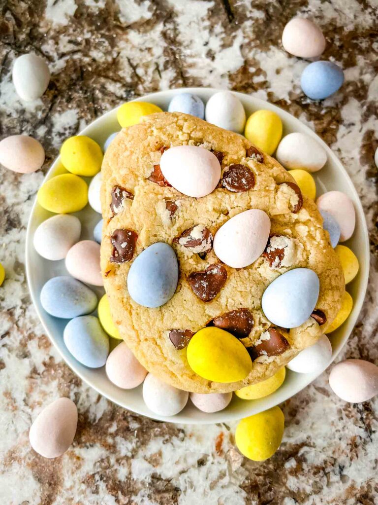 A large cookie on top of a pile of mini eggs