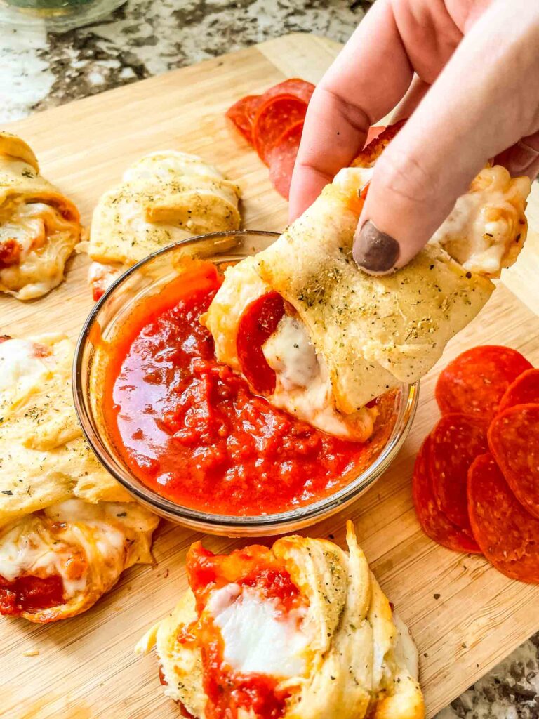 A hand dunking a roll into extra sauce
