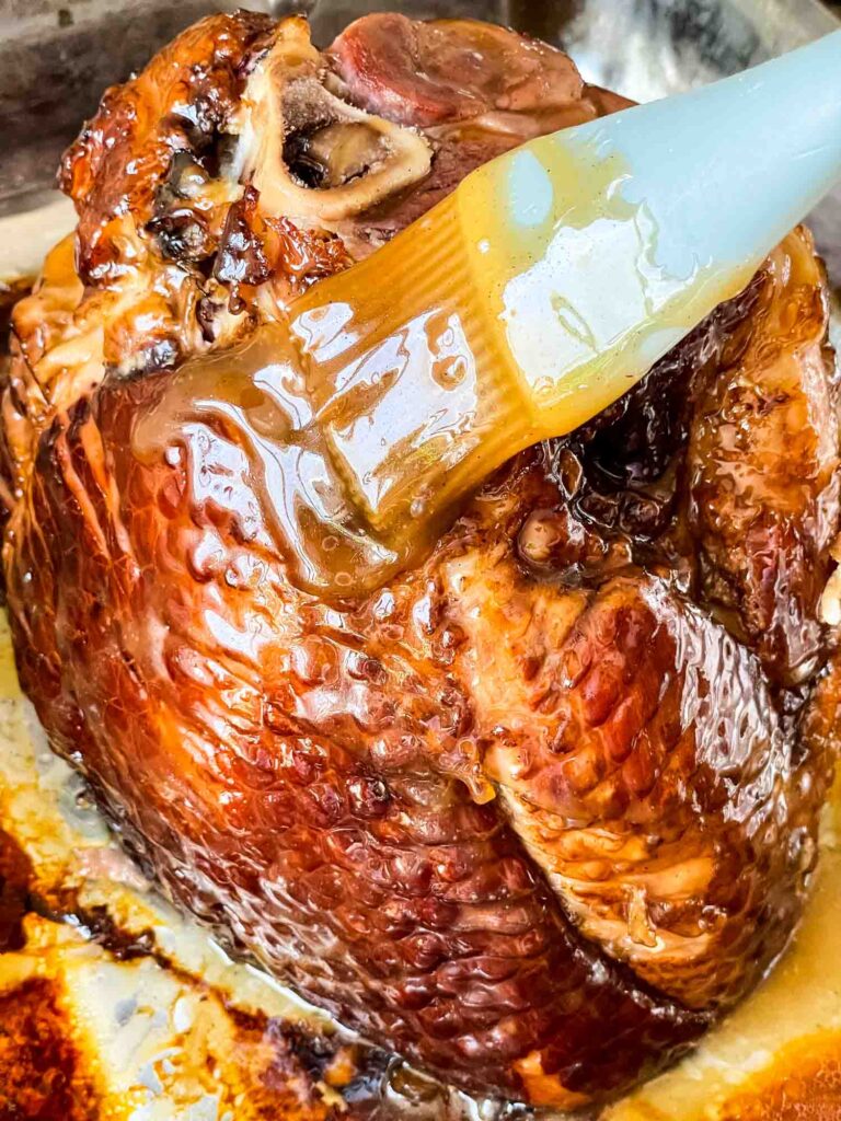 A brush basting the Spiral Ham with Brown Sugar Glaze