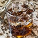 A glass of Black Russian Recipe with a jigger behind it