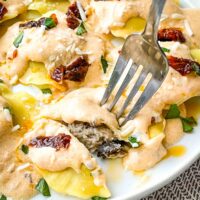 A fork cutting into a ravioli on a plate