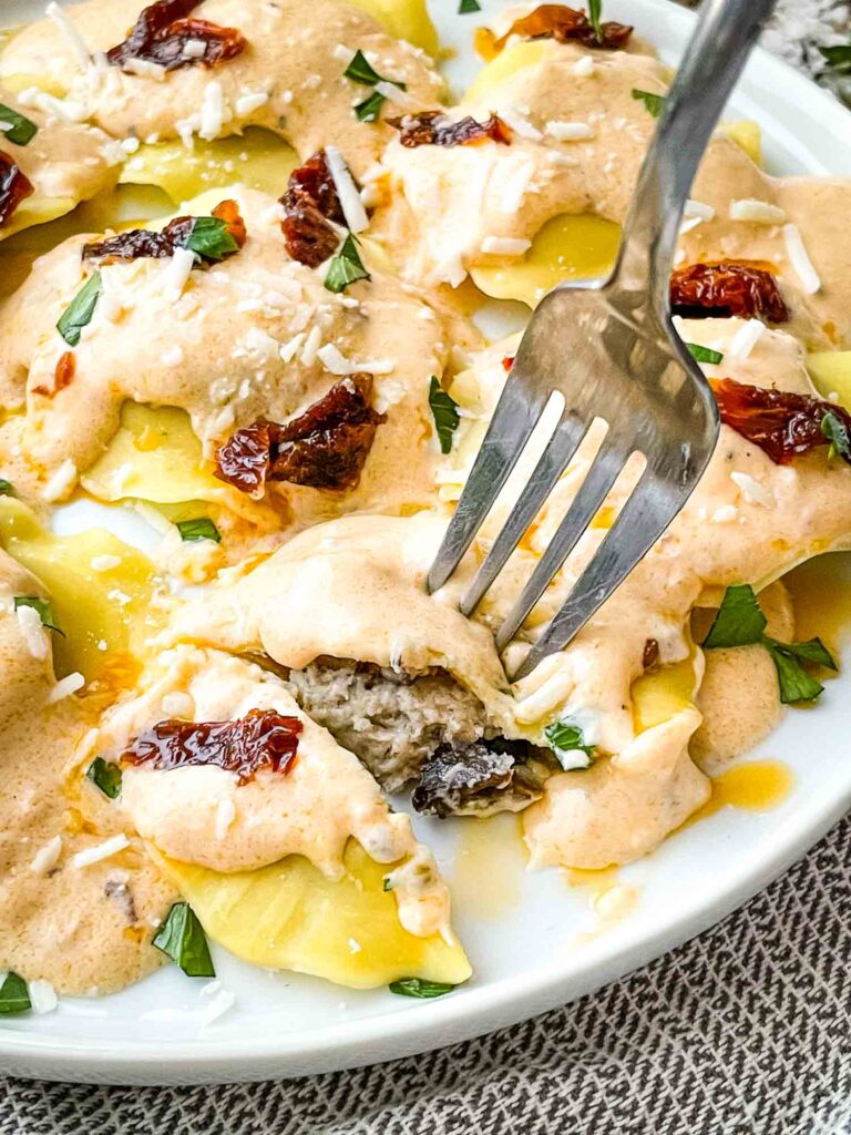 A fork cutting into a ravioli on a plate