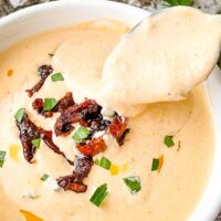 A spoon scooping into a bowl of Creamy Sundried Tomato Sauce