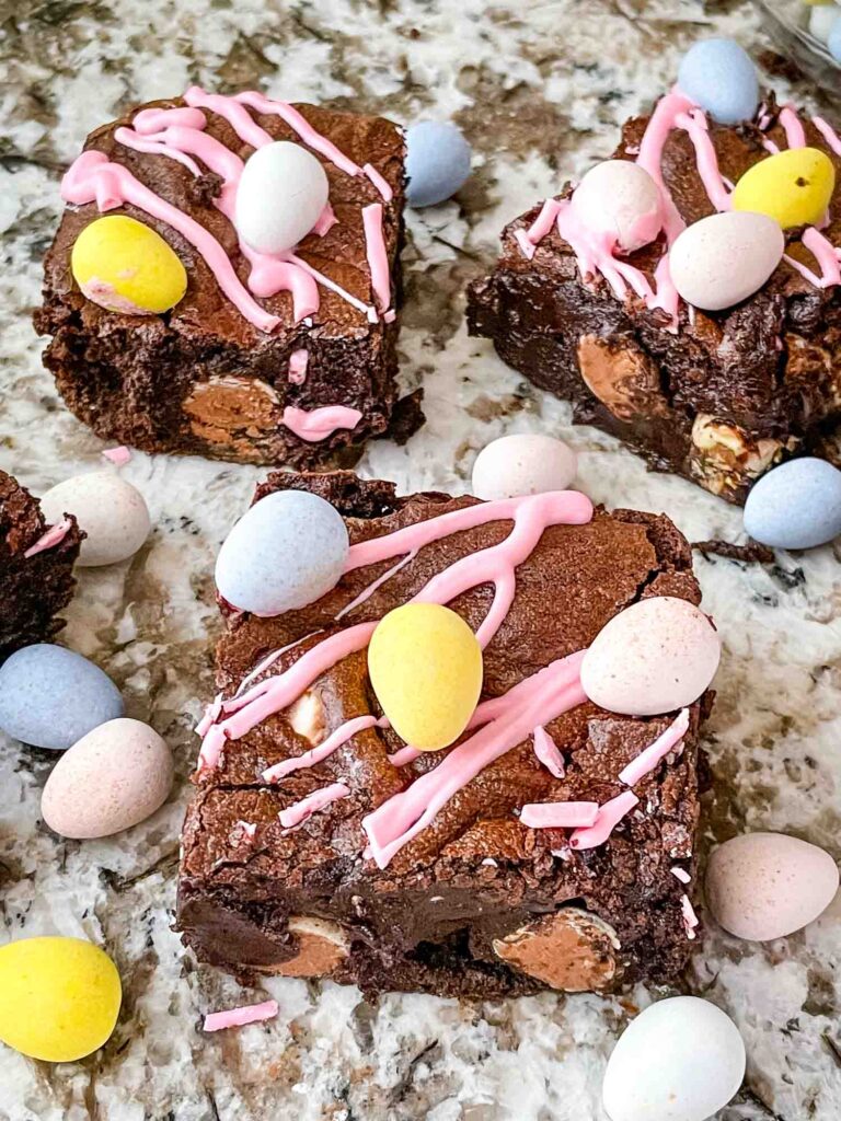 Mini Egg Brownies on a counter surrounded by chocolate mini eggs