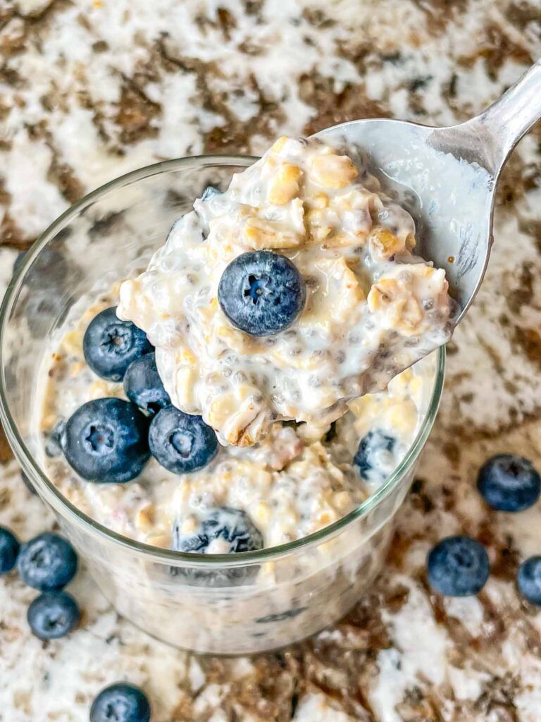 A spoon scooping Blueberry Overnight Oats out of the glass