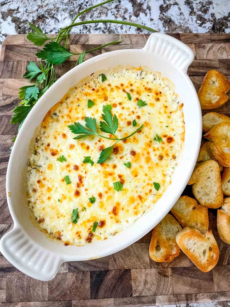 Top view of Copycat Olive Garden Smoked Mozzarella Fonduta in a baking dish with bread rounds next to it