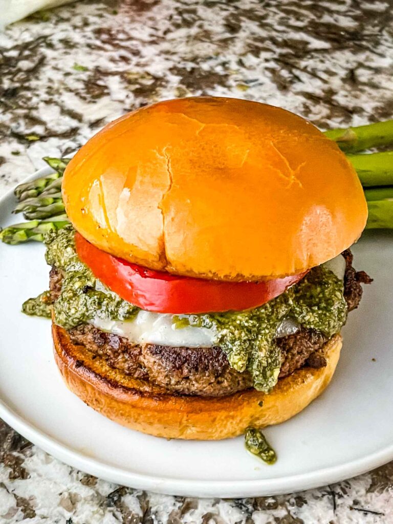 A full Pesto Turkey Burgers with tomato on a plate