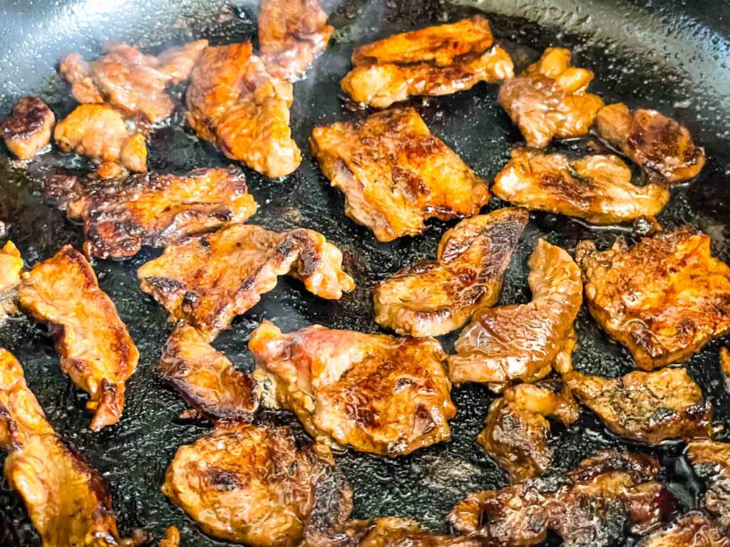 The steak browning in a skillet