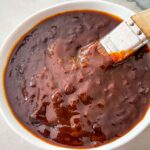 A basting brush dipping into a bowl of BBQ Sauce
