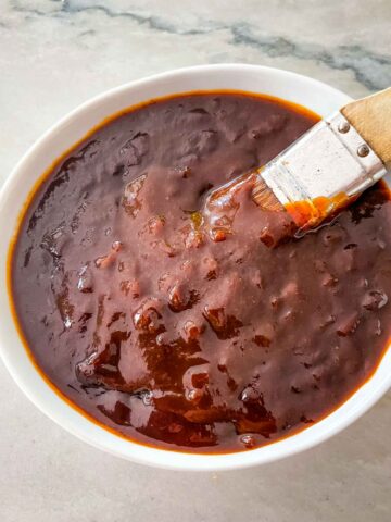 A basting brush dipping into a bowl of BBQ Sauce