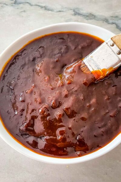 A basting brush dipping into a bowl of BBQ Sauce