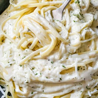 Close up of a fork twirling Alfredo Linguine in a bowl