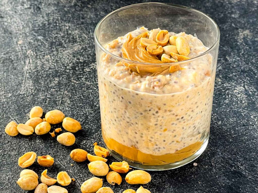 Peanut Butter Overnight Oats in a glass with peanuts around it