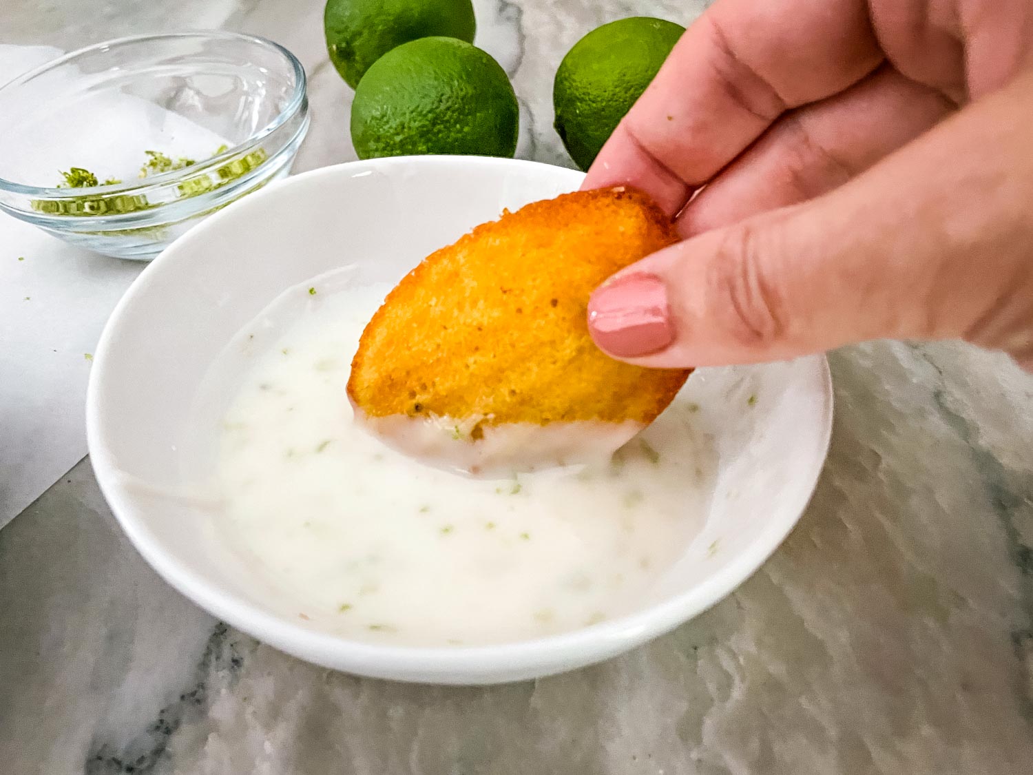 A hand dunking a cookie into the glaze