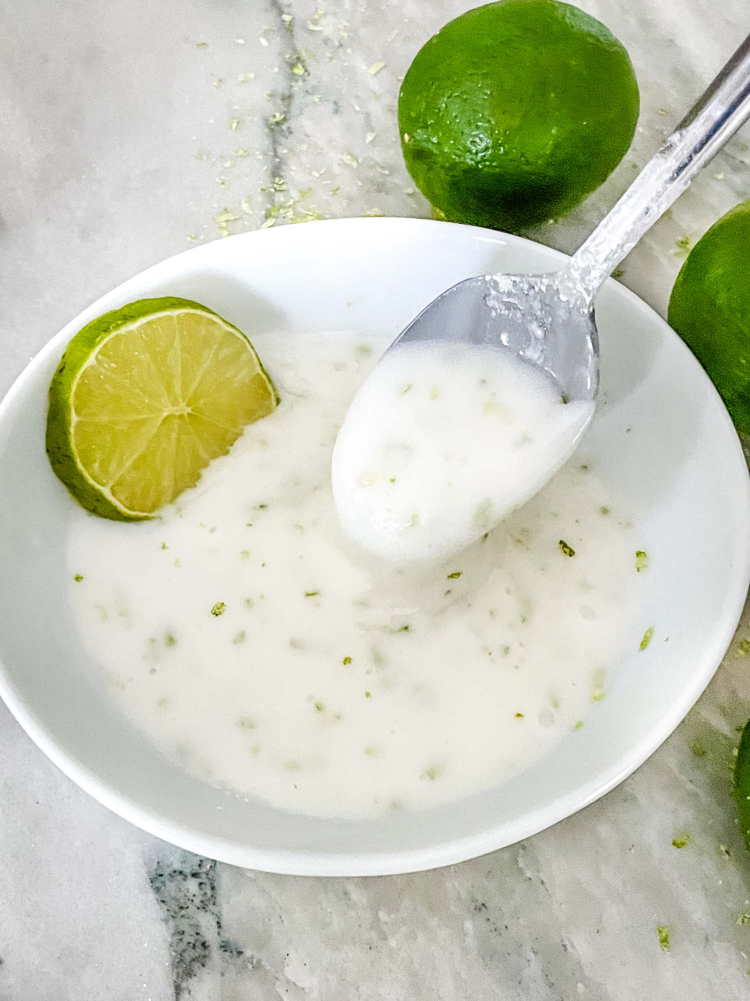 A spoon scooping Lime Glaze out of a white bowl