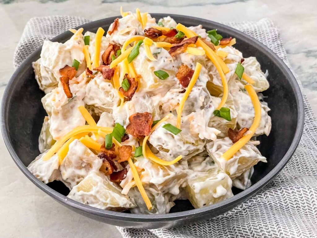 The finished Loaded Potato Salad in a bowl with more toppings on top for garnish