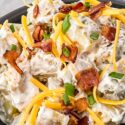 A close up of the Loaded Potato Salad with cheese, bacon, and green onions on top