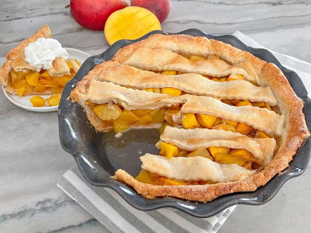 A Peach Mango Pie with a piece cut out and on a plate