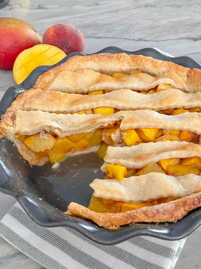 A Peach Mango Pie with a piece cut out of it
