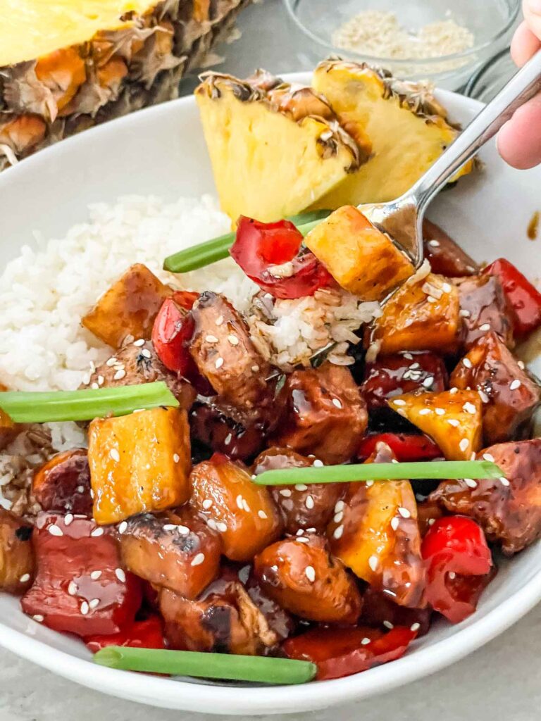 A fork digging into Pineapple Chicken in a bowl