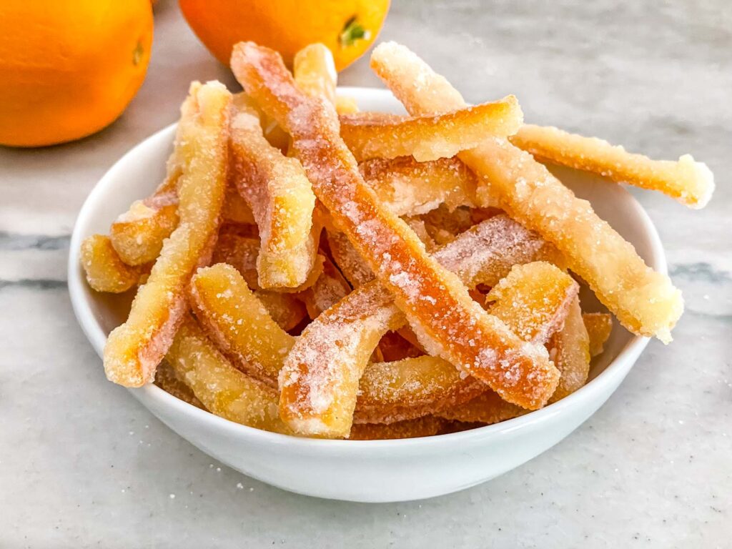 Candied Orange Peel piled in a white bowl on a counter