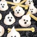 Halloween Ghost Meringues scattered on black cloth with small bones