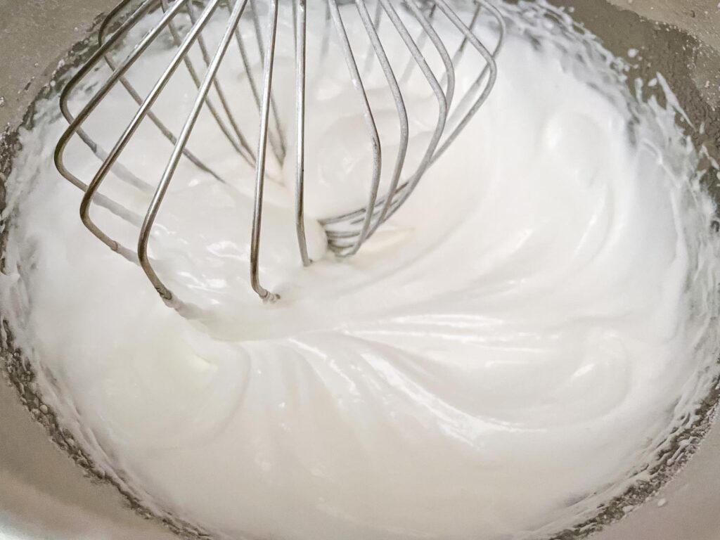 The meringue in a mixing bowl at the shiny and thick state