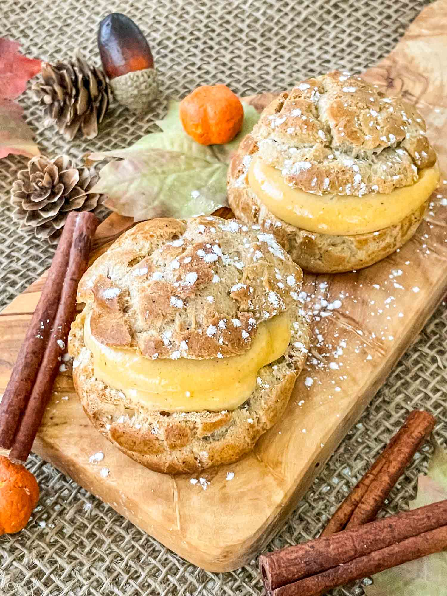 Pumpkin Spice Cream Puffs filled and on a small cutting board