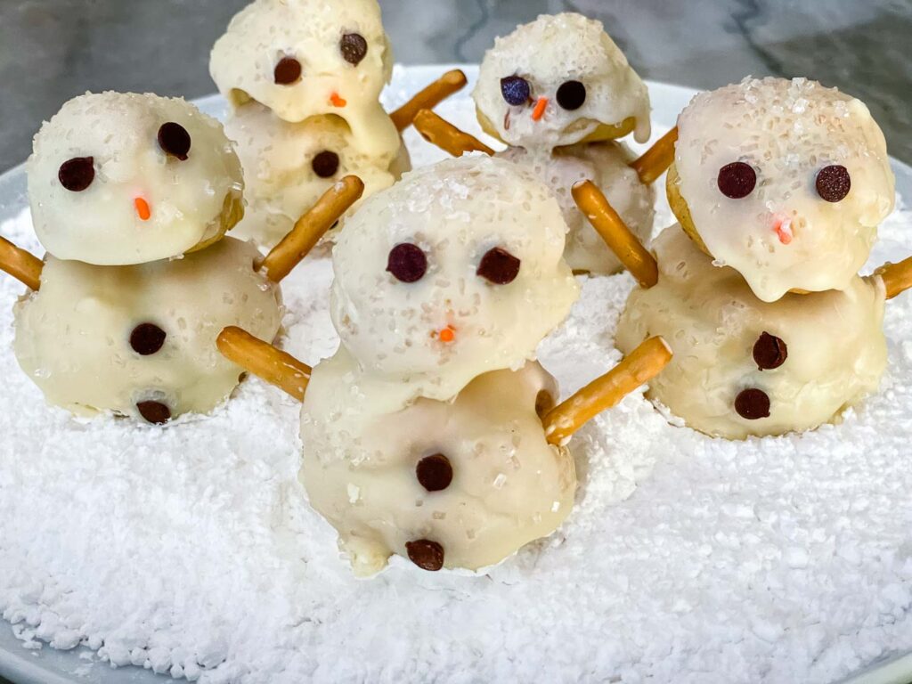 Snowman Cream Puffs sitting in powdered sugar