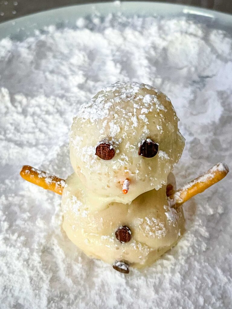A Snowman Cream Puff sitting in powdered sugar