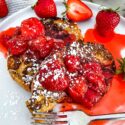 A fork digging into Strawberry French Toast on a white plate