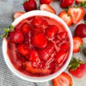 Strawberry Sauce in a small white bowl surrounded by fruit