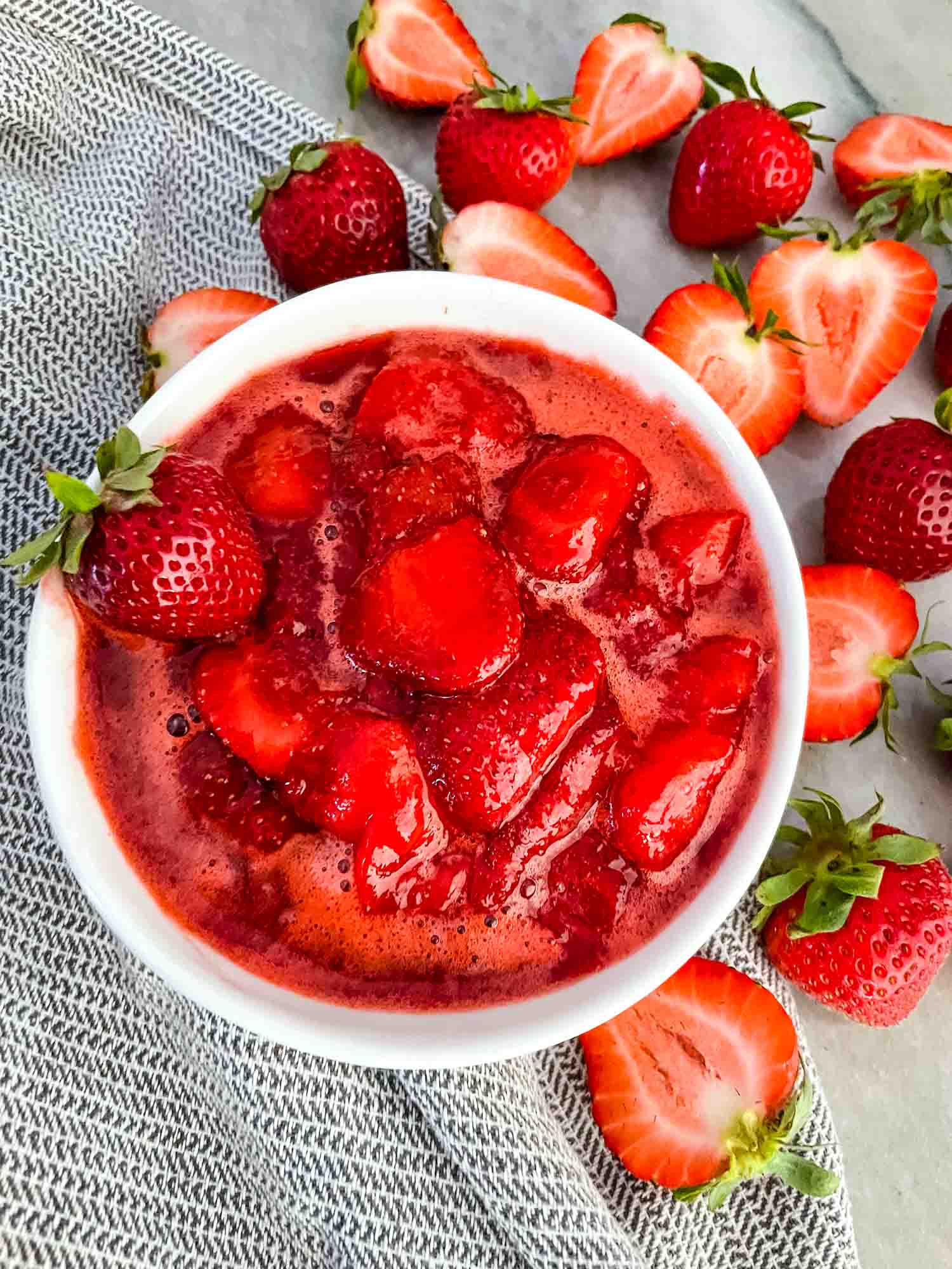 Strawberry Sauce in a small white bowl surrounded by fruit