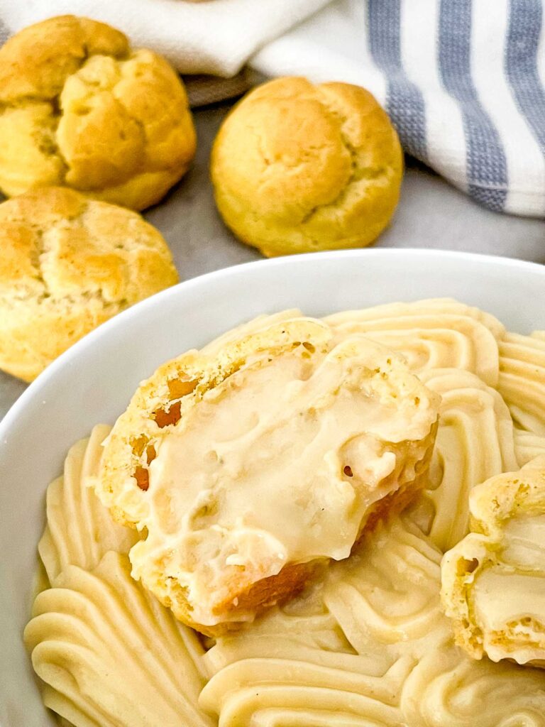 A cream puff filled with Vanilla Pastry Cream sitting on top of more pastry cream in a bowl