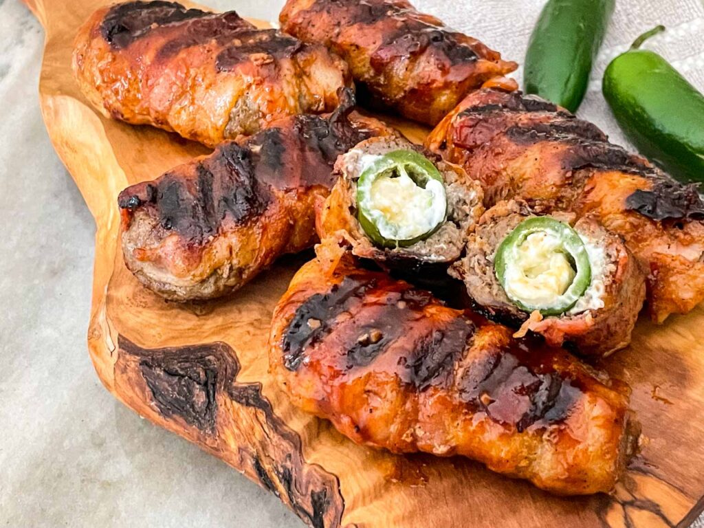 Armadillo Eggs in a pile on a piece of wood with one cut in half
