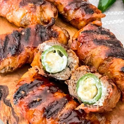 Armadillo Eggs on a cutting board with one cut in half