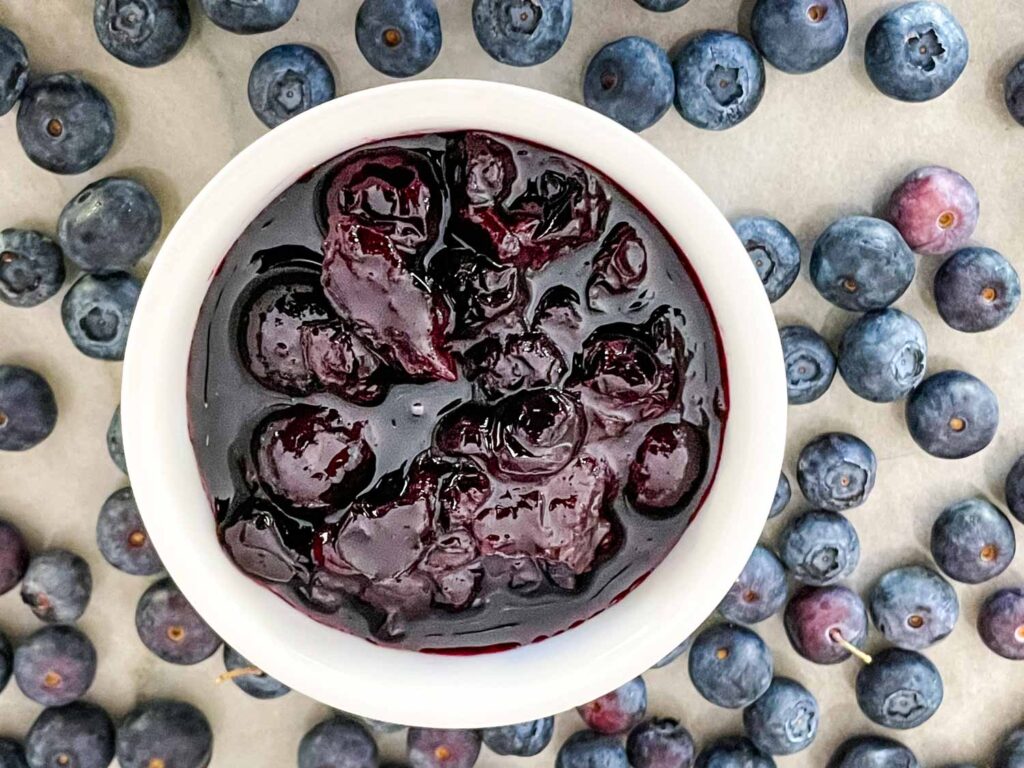 Top view of Blueberry Compote in a white ramekin surrounded by berries