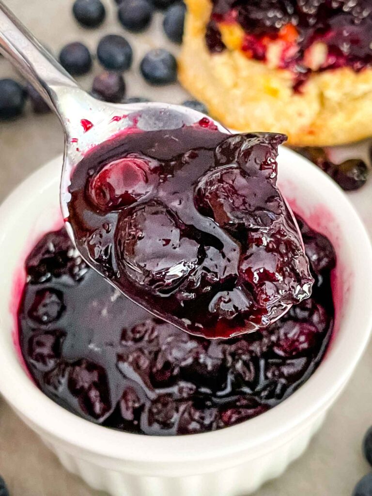A spoon scooping Blueberry Compote out of a white dish